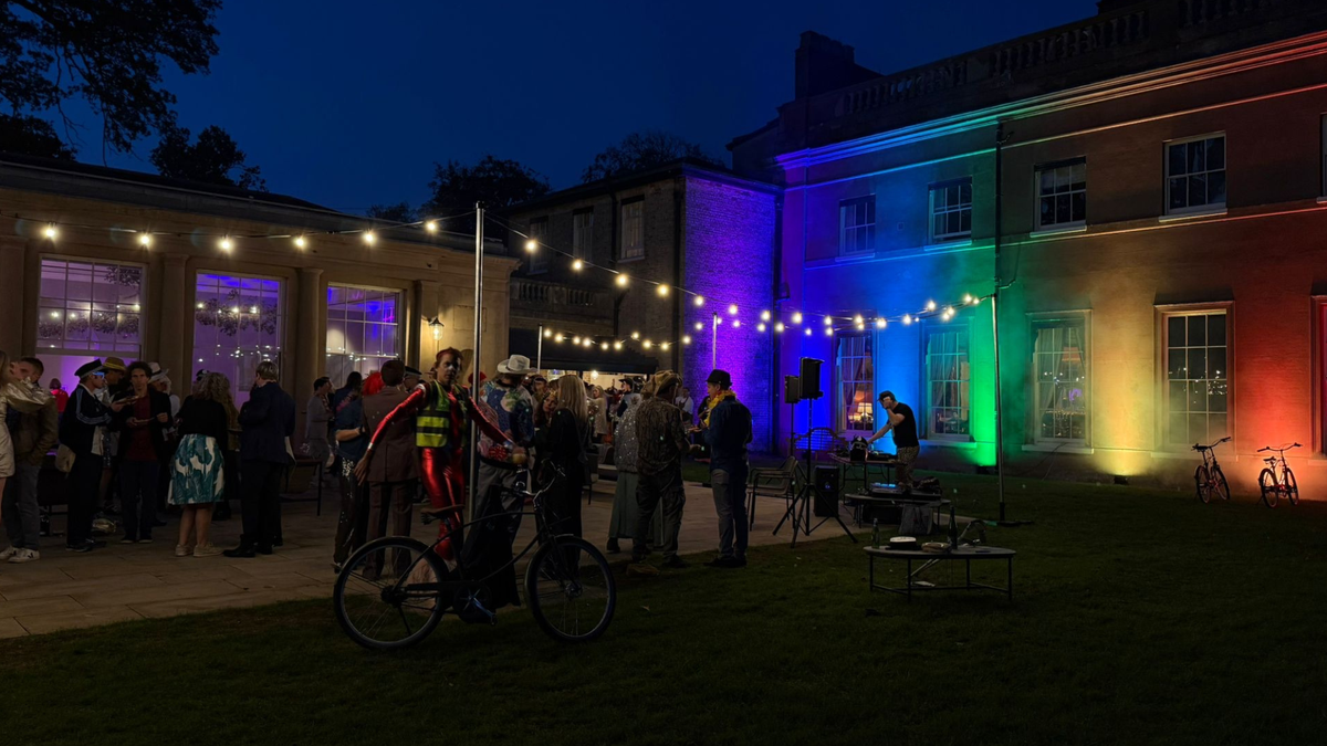 Festoon lights over a courtyard event with a lit building by MAV Hire
