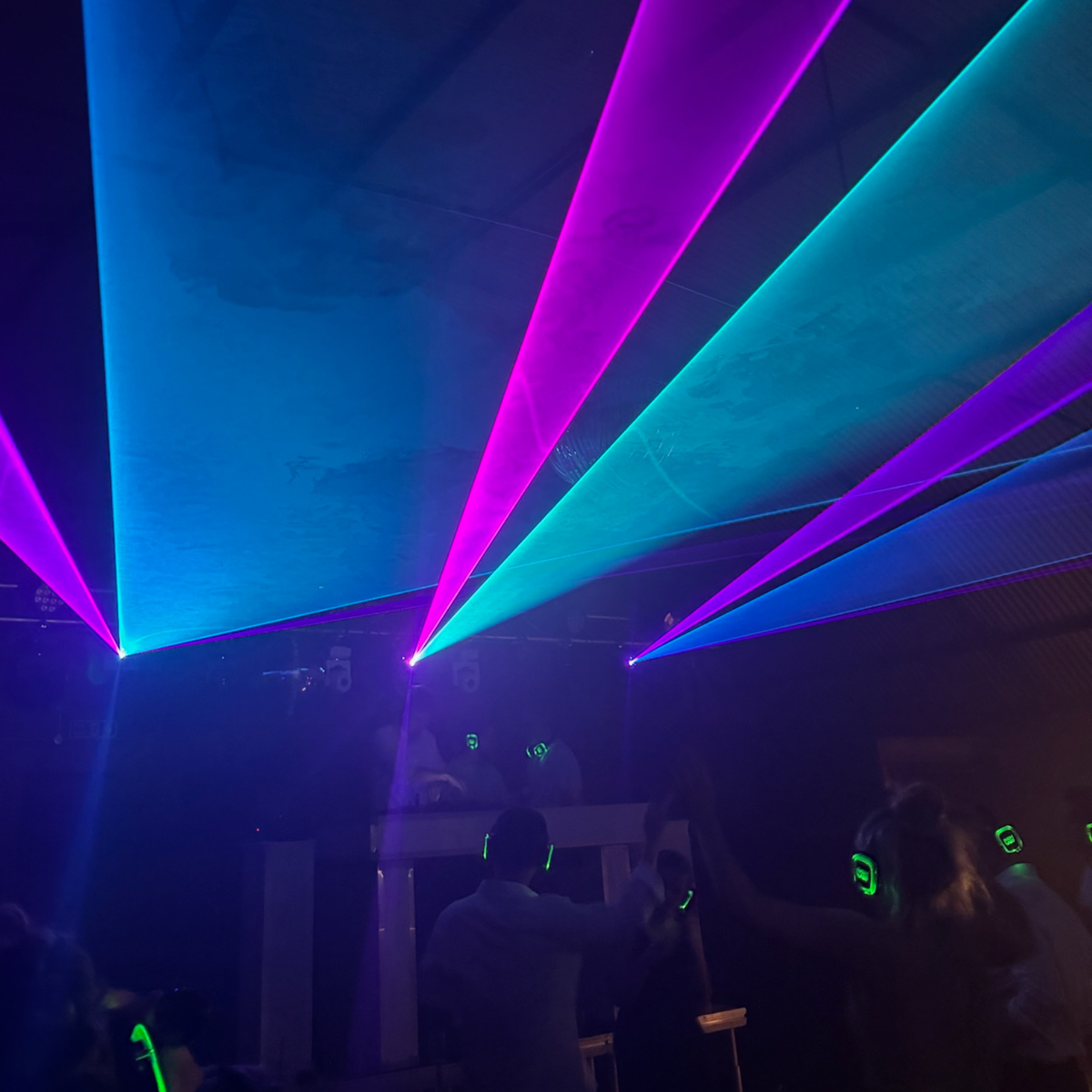 Silent disco with glowing headphones under laser lights at an event by MAV Hire